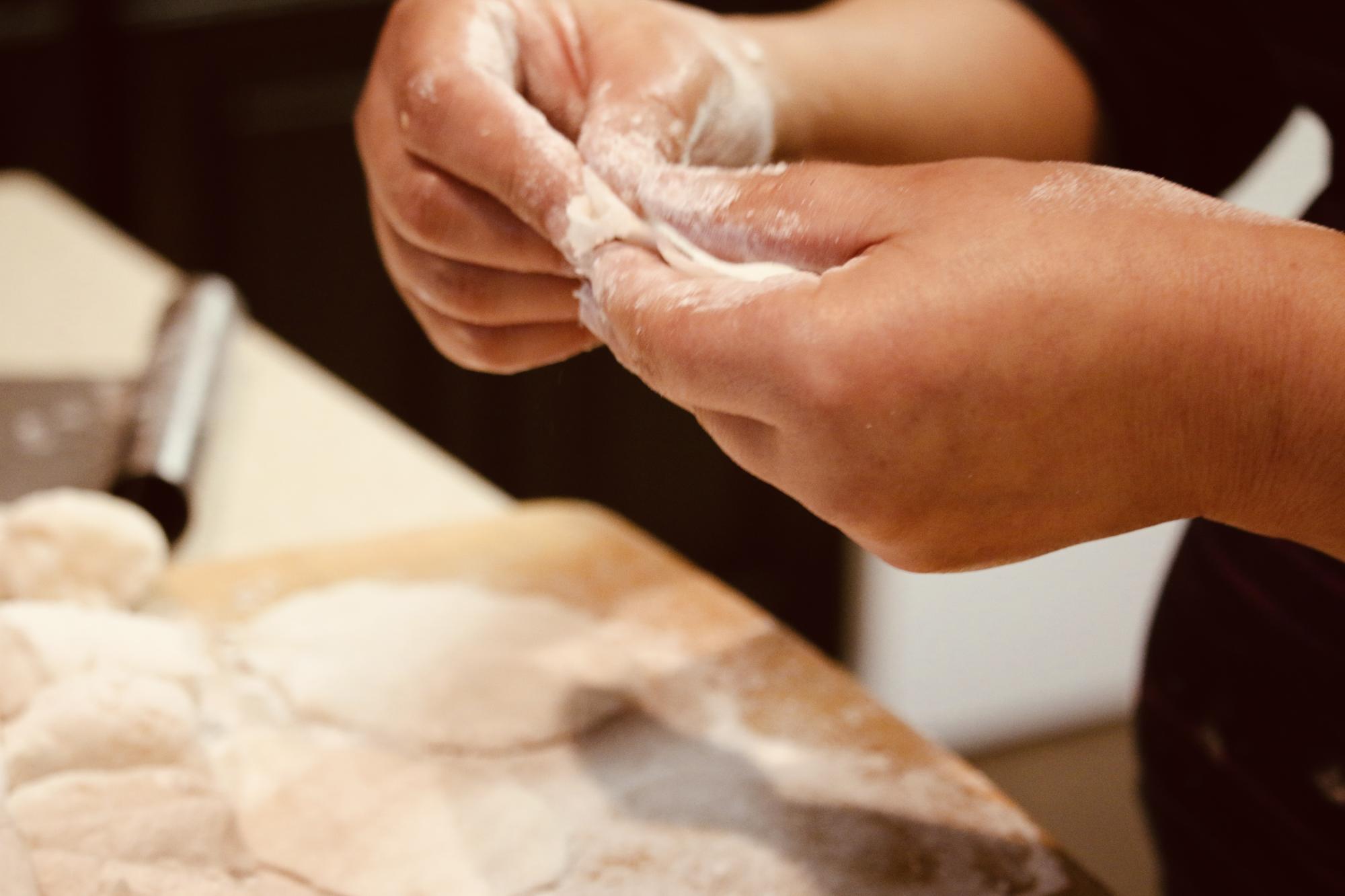 hands kneading bread dough in warm kitchen